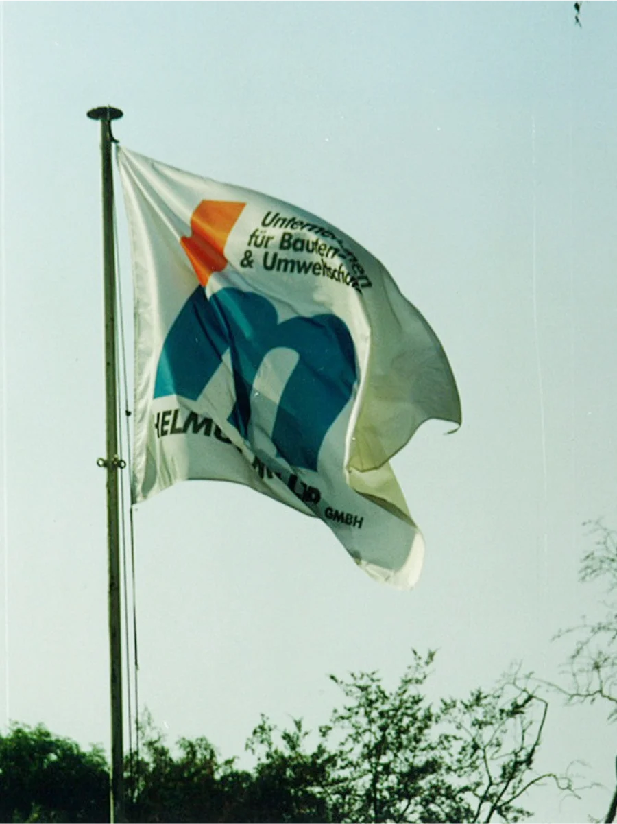 Wehende Flagge der Helmut Müller GmbH mit Unternehmenslogo im Wind